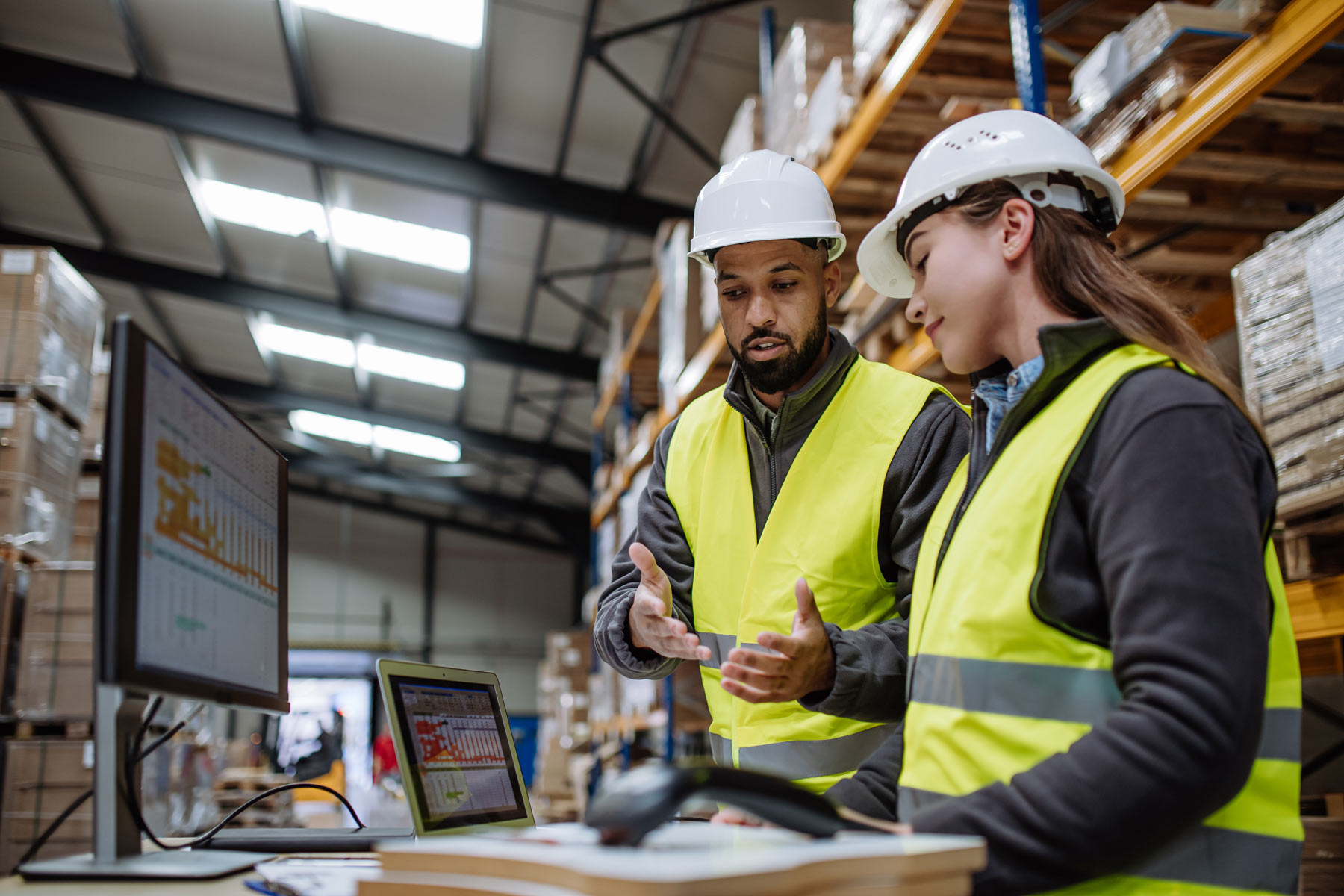 Logistics team reviewing freight data on monitors in a warehouse