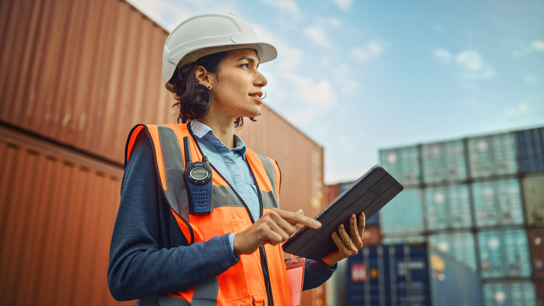 Logistics coordinator reviewing shipment data on a tablet at a container yard