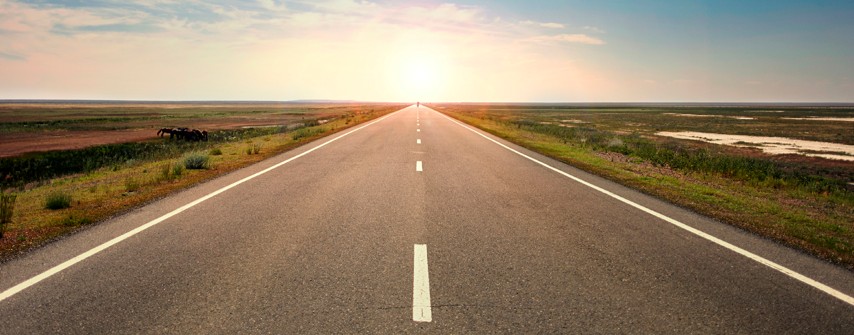 Open road stretching toward the horizon at sunrise