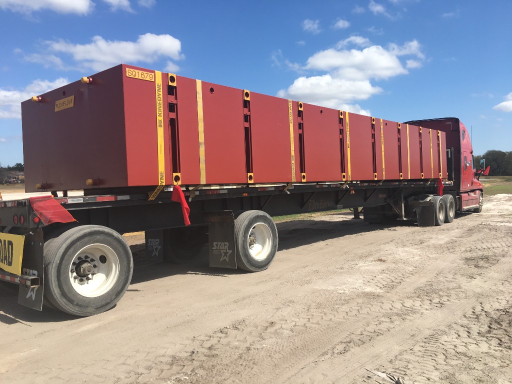 Flatbed truck with oversized industrial freight secured for transport